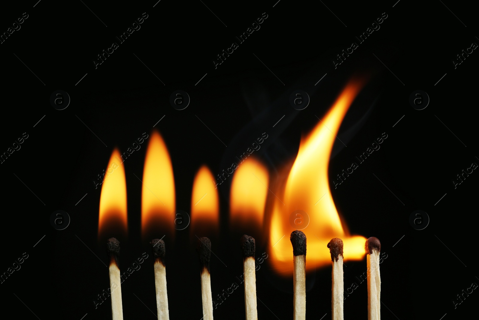 Photo of Line of burning matches on black background