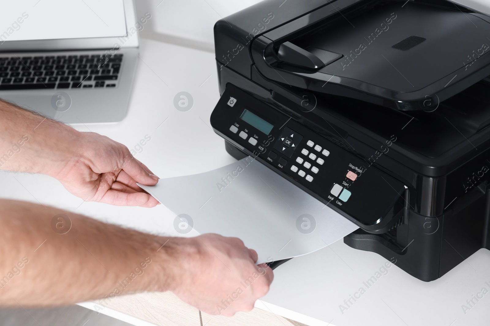 Photo of Man using modern printer at white desk in office, closeup