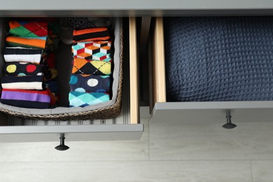 Photo of Chest of drawers with different folded clothes indoors, top view