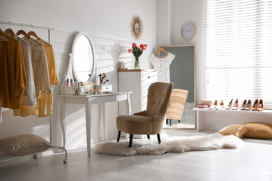 Stylish room interior with elegant dressing table, mirror and comfortable chair