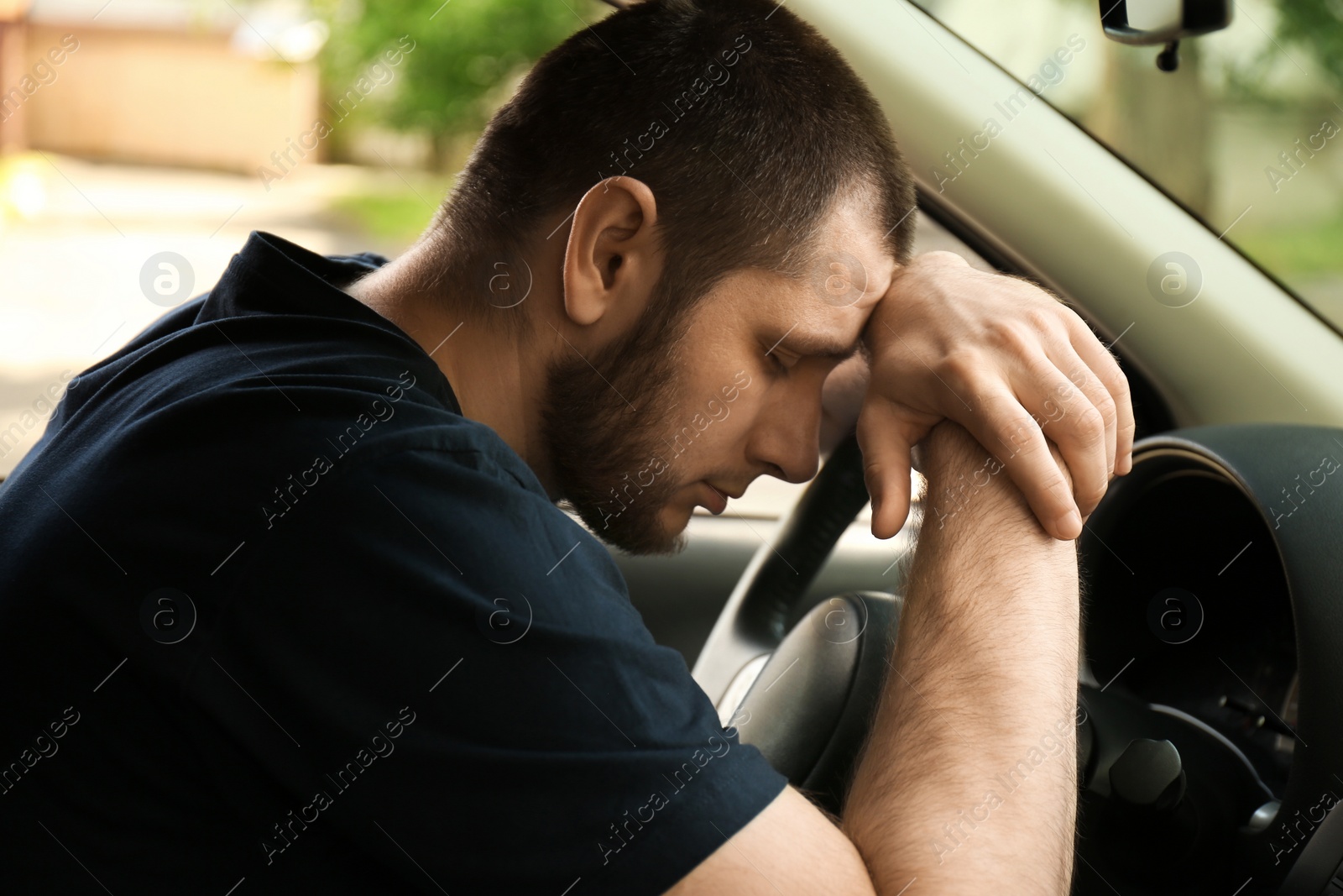 Photo of Tired man sleeping on steering wheel in his car