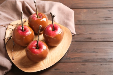 Photo of Plate with delicious caramel apples on wooden background