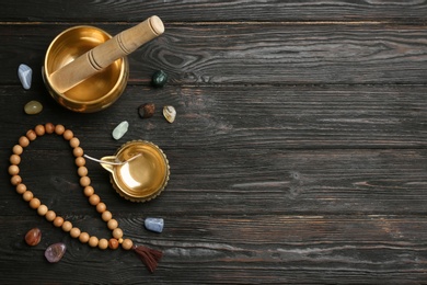 Flat lay composition with golden singing bowl on black wooden table, space for text. Sound healing