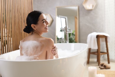 Photo of Beautiful young woman taking bubble bath at home