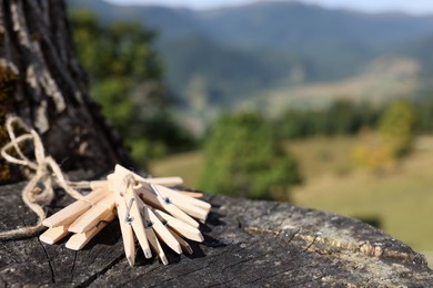 Photo of Set of wooden clothes pins on tree stump outdoors. Space for text