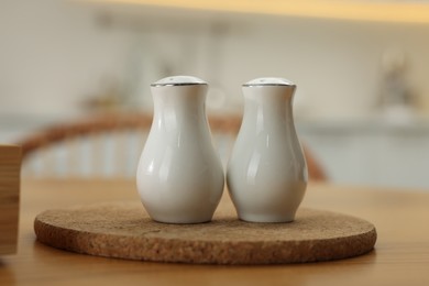 Photo of White ceramic salt and pepper shakers on wooden table indoors