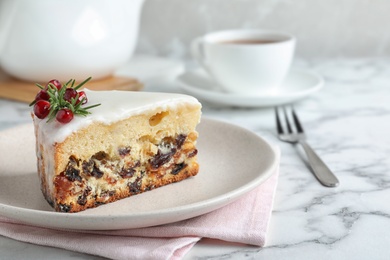 Photo of Slice of traditional Christmas cake decorated with rosemary and pomegranate seeds on white marble table