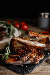 Tasty grilled ribs with rosemary on wooden table