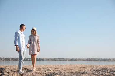 Photo of Happy couple walking along beach on summer day