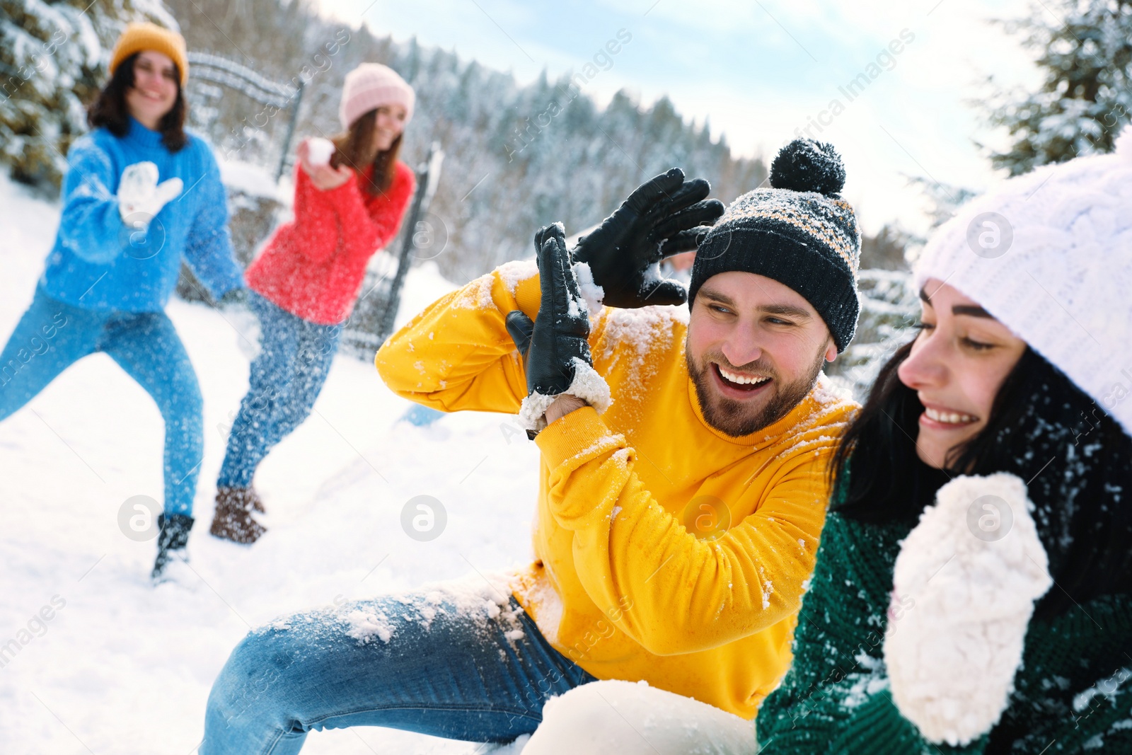 Photo of Group of friends playing snowballs outdoors. Winter vacation