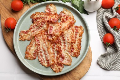 Photo of Delicious fried bacon slices and other products on white wooden table, flat lay