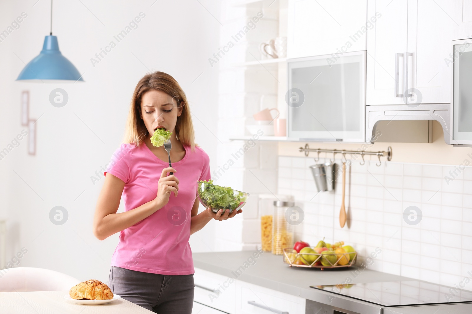 Photo of Woman choosing between vegetable salad and dessert in kitchen. Healthy diet