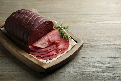 Tasty bresaola, peppercorns and rosemary on wooden table. Space for text