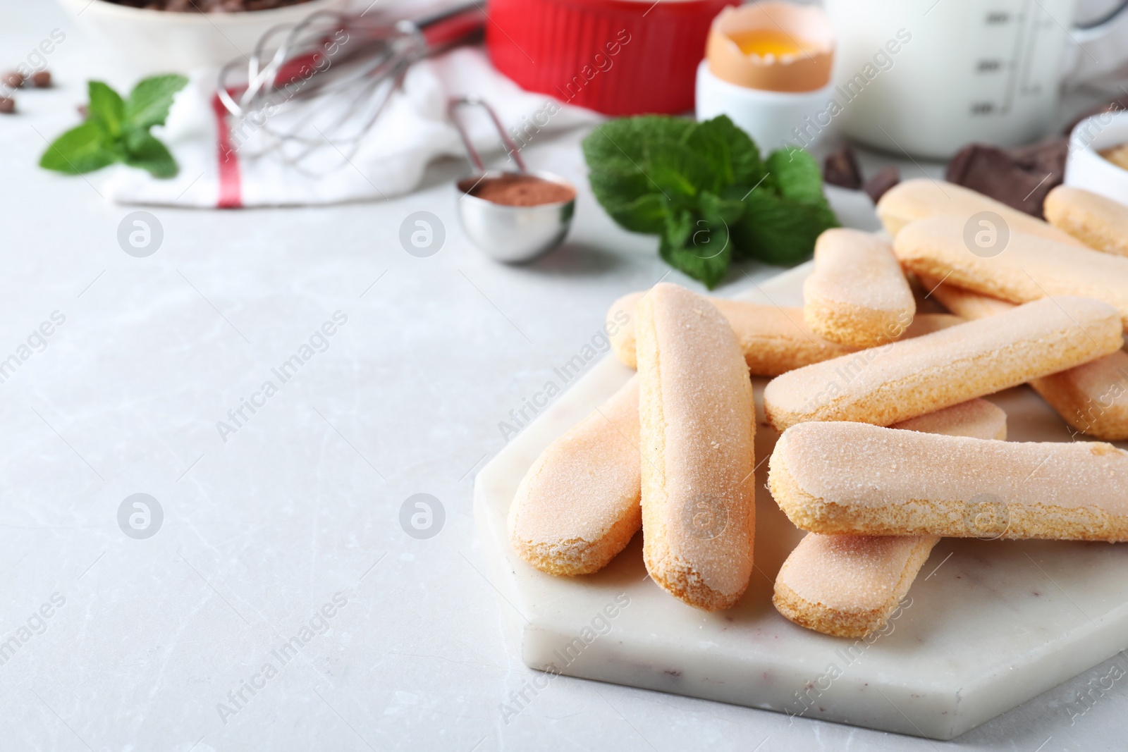 Photo of Tasty cookies and other tiramisu ingredients on light grey table, space for text