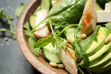 Delicious salad with chicken, arugula and avocado in bowl on table, closeup