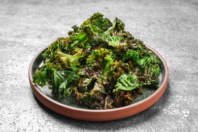 Photo of Tasty baked kale chips on grey table