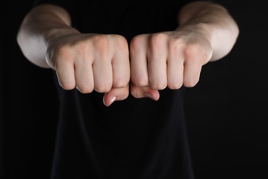 Photo of Man showing fists with space for tattoo on black background, closeup