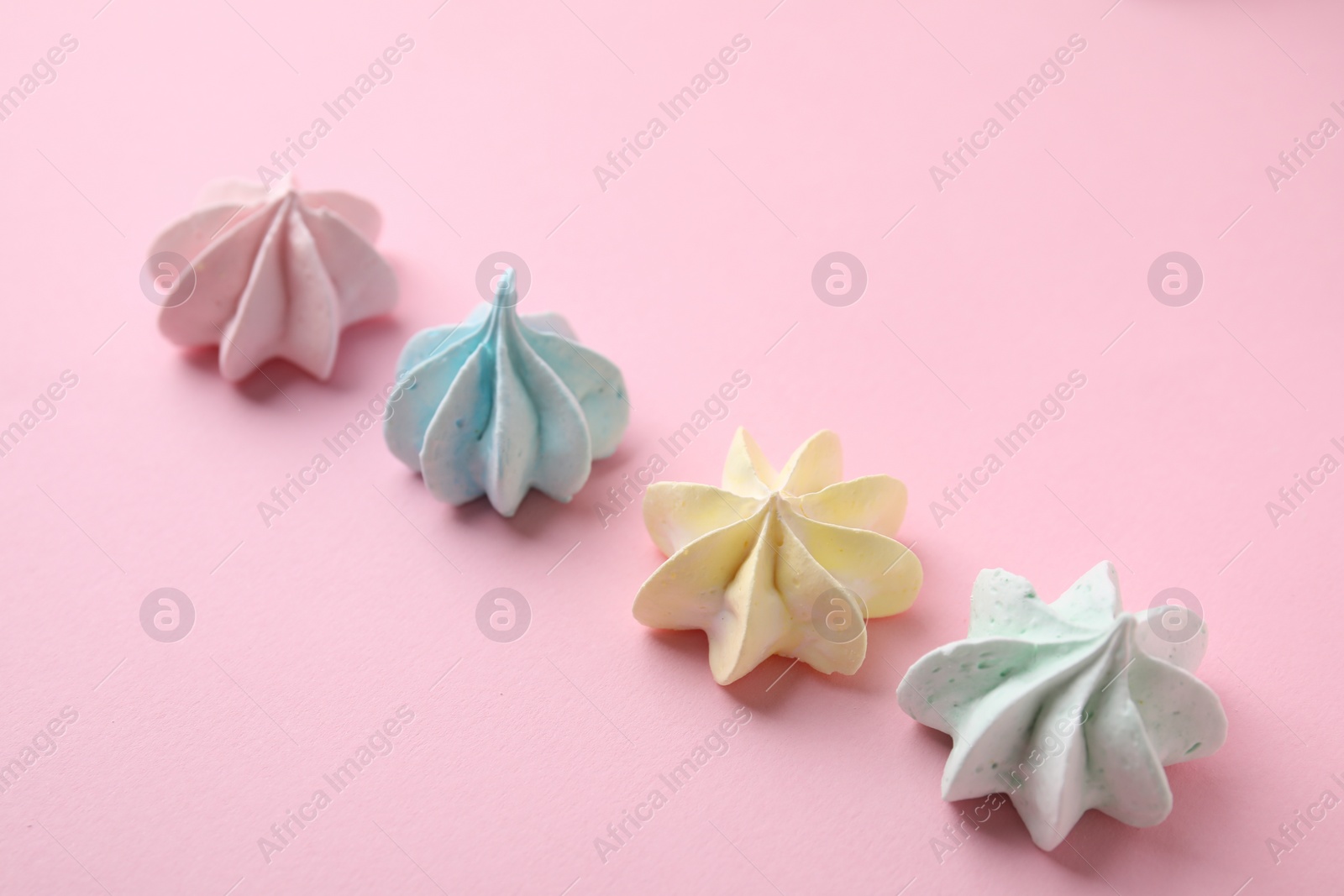 Photo of Many tasty meringue cookies on pink background