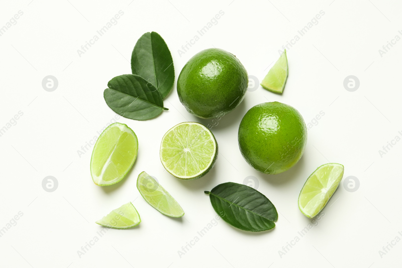 Photo of Whole and cut fresh ripe limes with green leaves on white background, flat lay