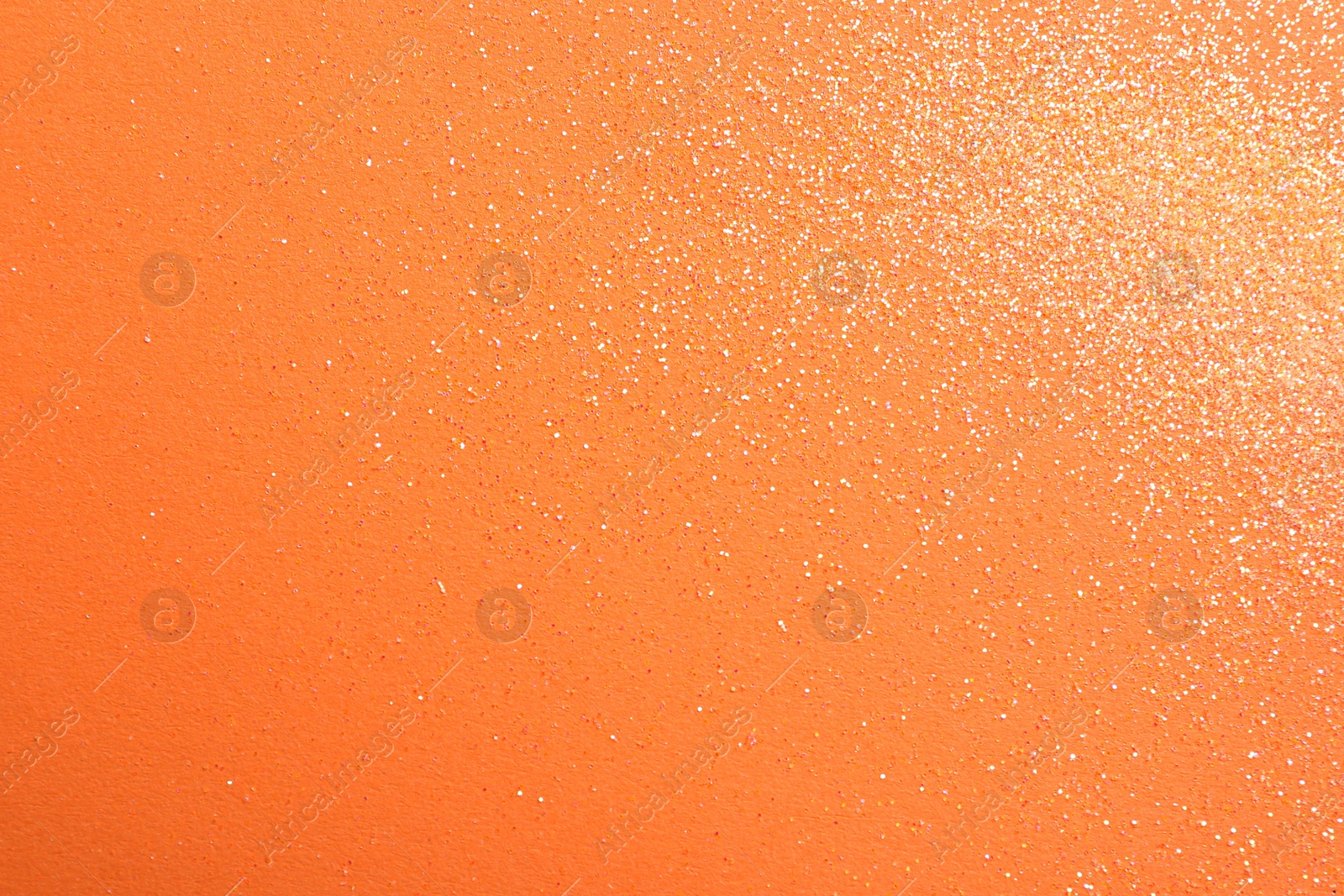 Photo of Shiny bright glitter on orange background, flat lay. Space for text