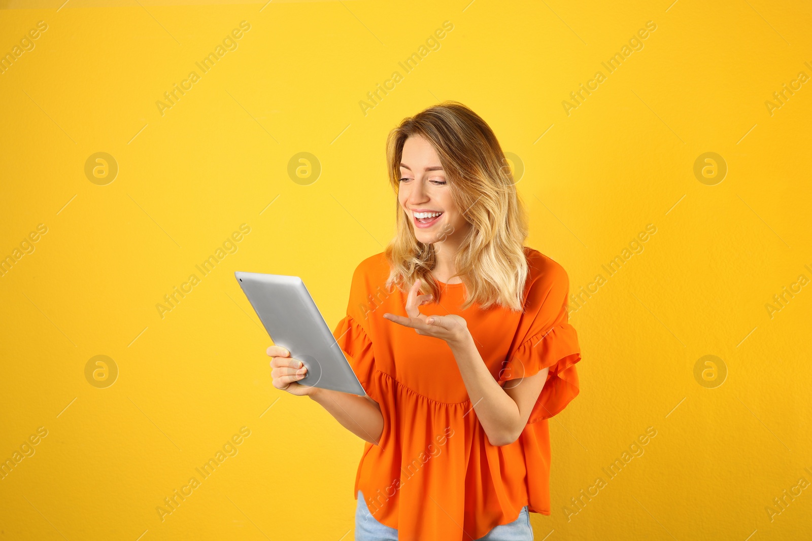 Photo of Woman using tablet for video chat on color background