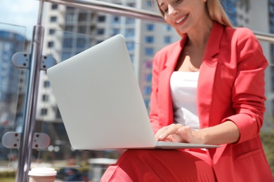 Businesswoman using laptop on city street, closeup