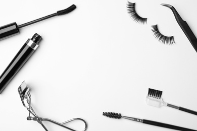 Flat lay composition of professional makeup tools and false eyelashes on white background, space for text