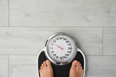 Woman standing on scales indoors, top view with space for text. Overweight problem