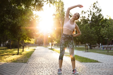 Young woman stretching before morning run in park. Space for text