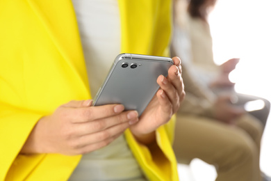 Young woman using modern smartphone indoors, closeup