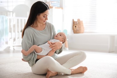 Photo of Young woman with her cute baby at home, space for text