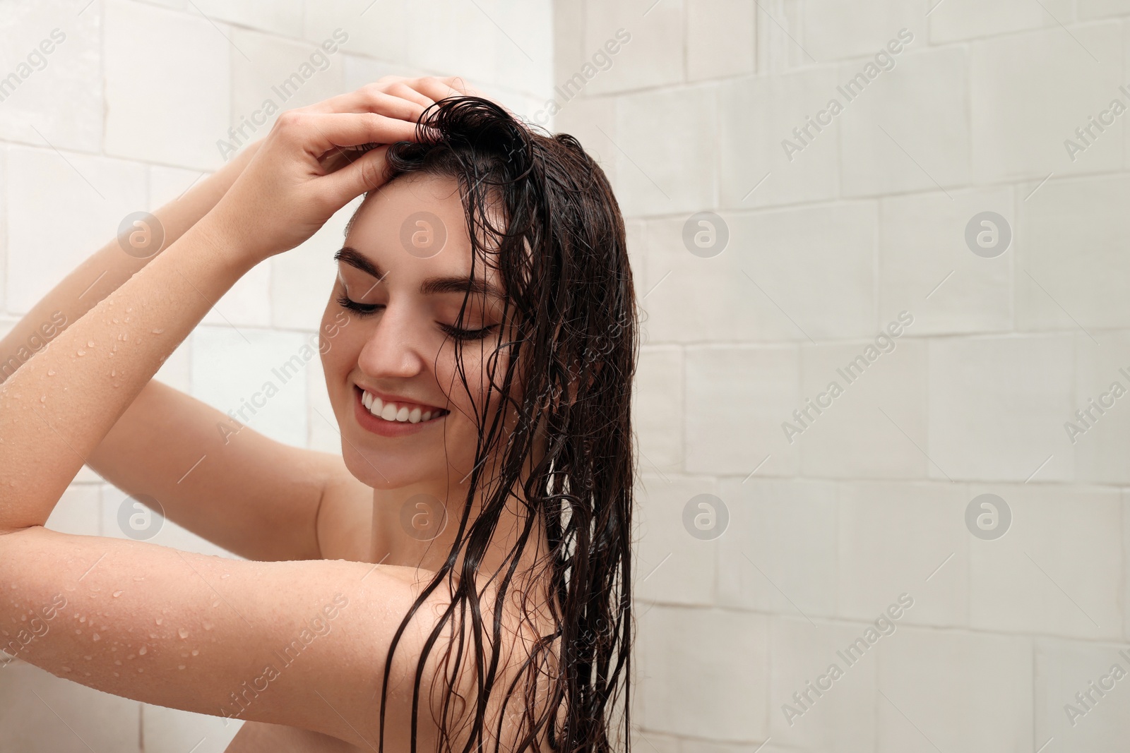 Photo of Happy woman washing hair while taking shower at home