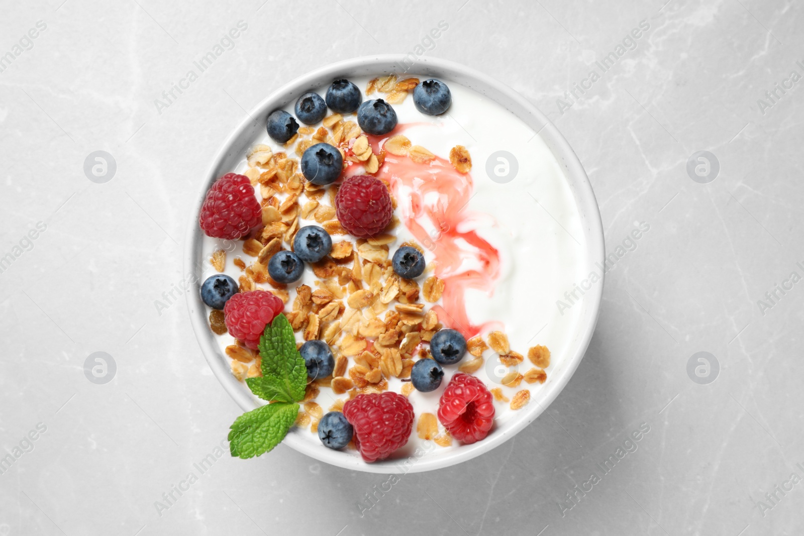 Photo of Tasty homemade granola with yogurt and berries on light table, top view. Healthy breakfast