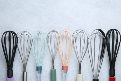 Photo of Different whisks on gray table, flat lay. Space for text