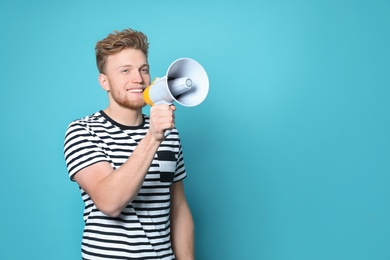 Young man with megaphone on color background. Space for text