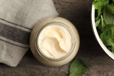 Photo of Jar of delicious mayonnaise and fresh spinach on wooden table, flat lay