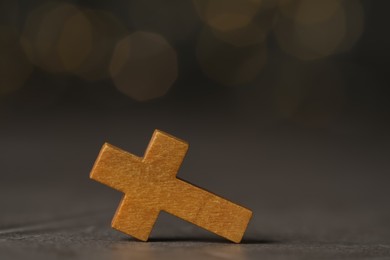 Wooden Christian cross on grey table against blurred lights, space for text