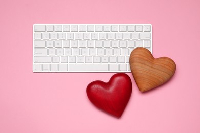 Photo of Long-distance relationship concept. Decorative hearts and keyboard on pink background, flat lay