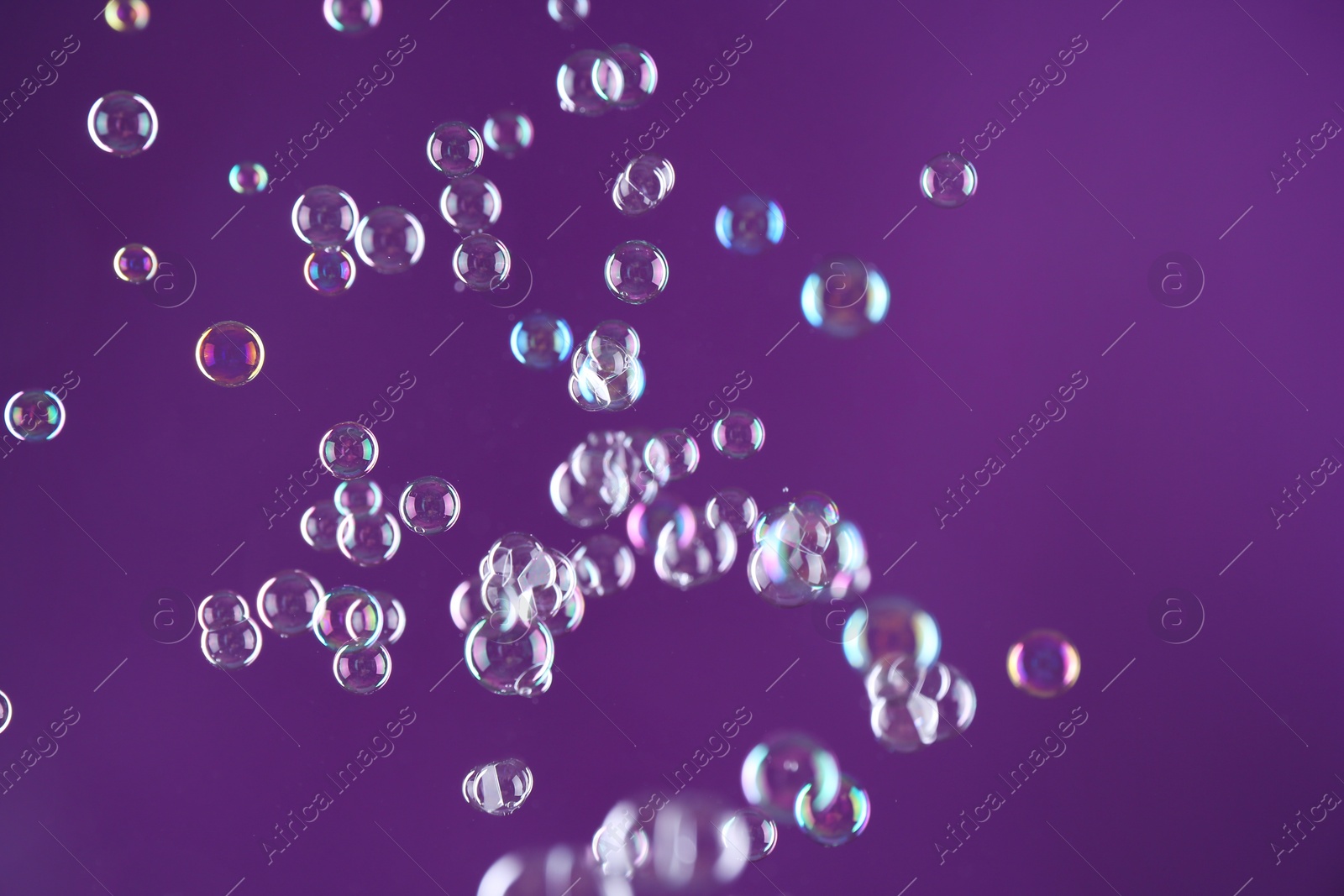 Photo of Beautiful transparent soap bubbles on purple background