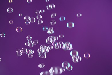 Beautiful transparent soap bubbles on purple background