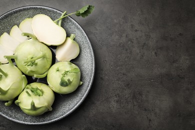 Photo of Whole and cut kohlrabi plants on grey table, top view. Space for text