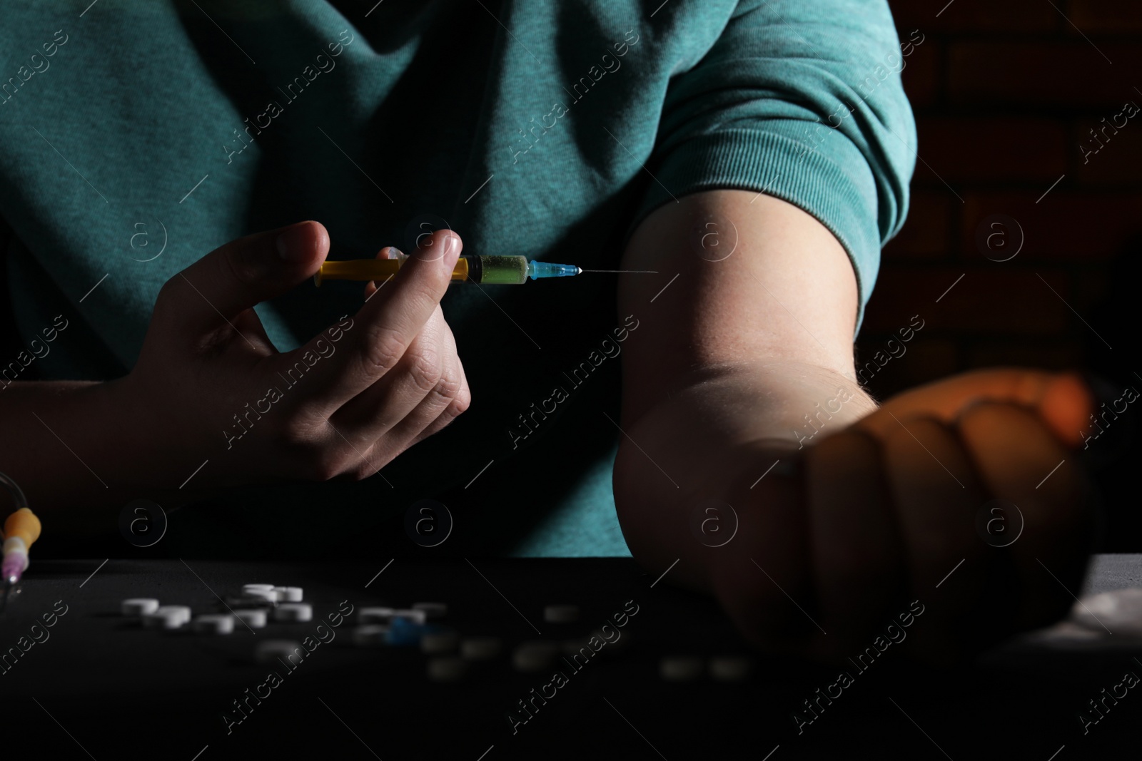 Photo of Addicted man taking drugs at black table, closeup