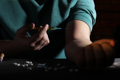 Addicted man taking drugs at black table, closeup