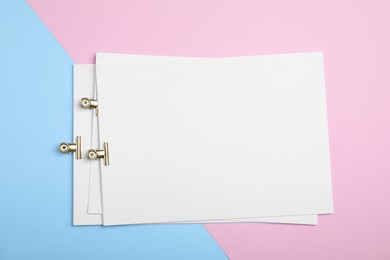 Photo of Sheets of paper with clips on color background, top view