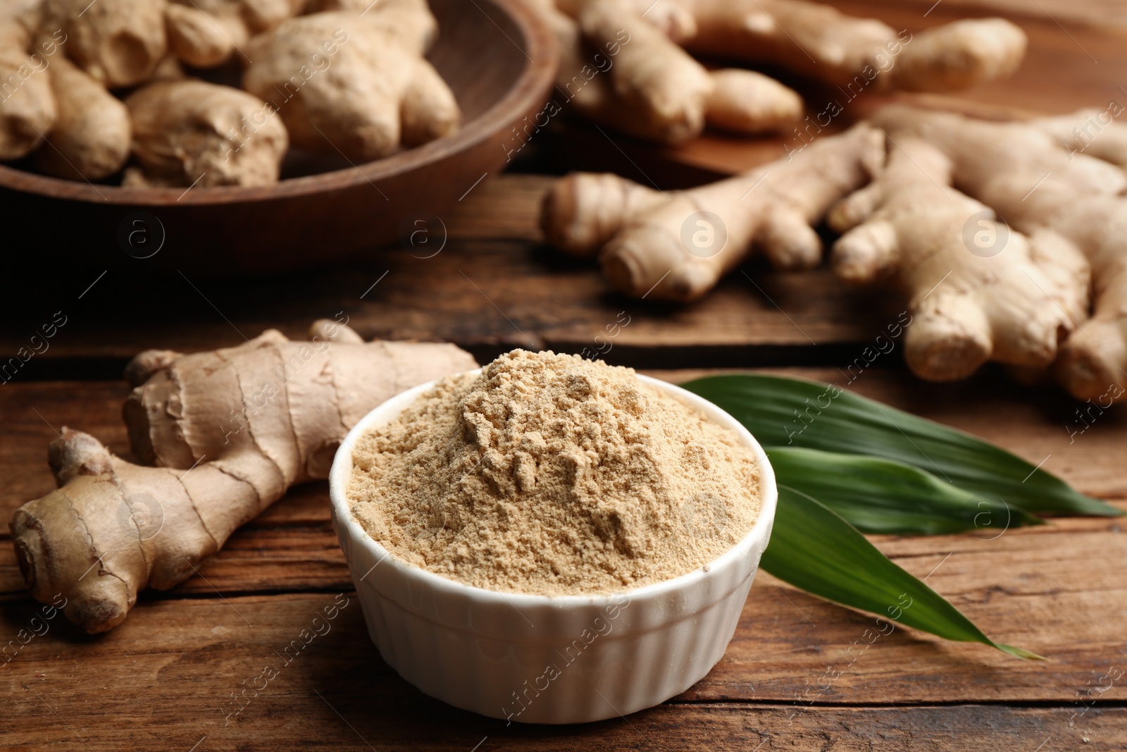 Photo of Dry ginger powder, fresh root and leaves on wooden table