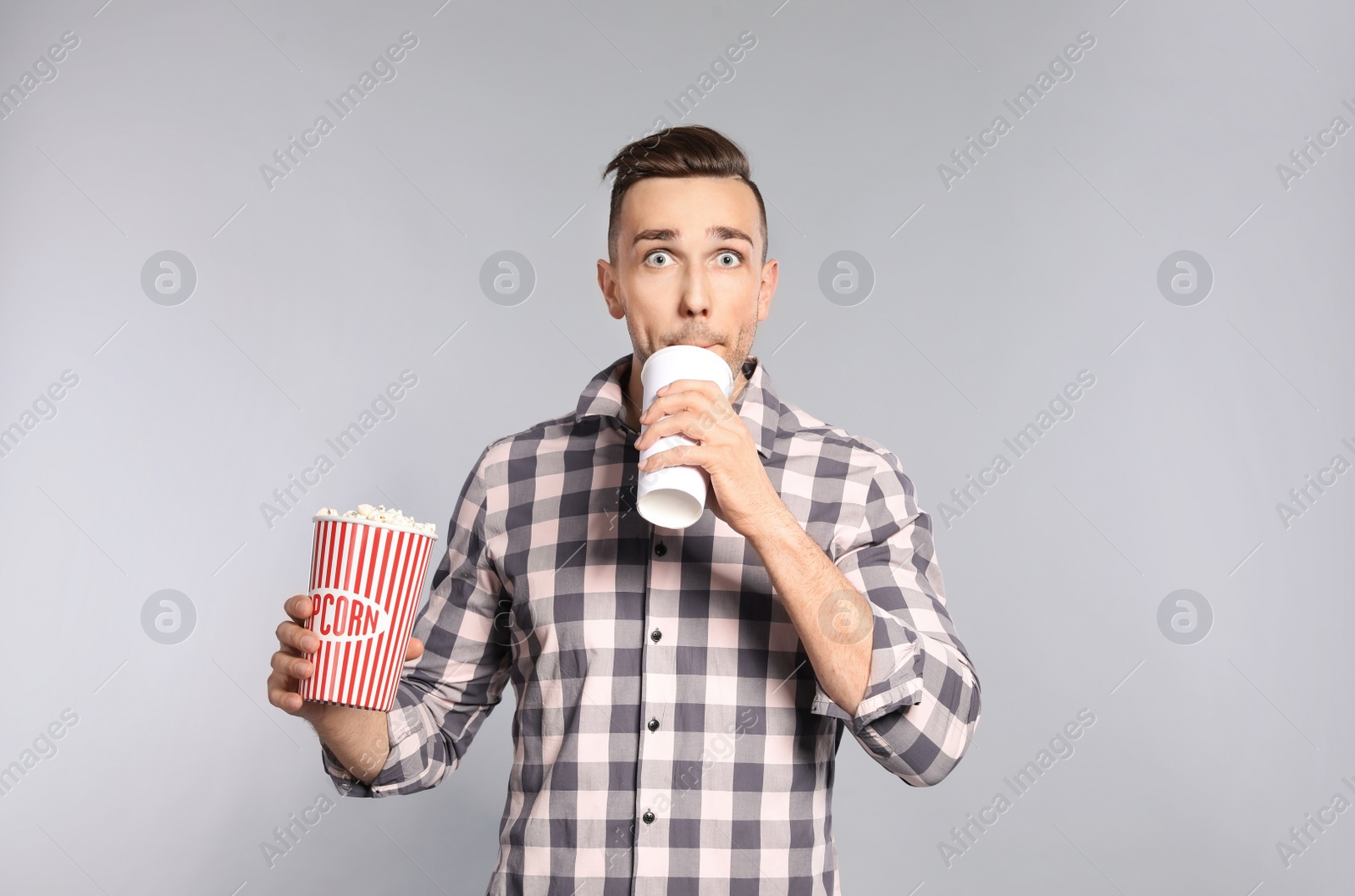 Photo of Emotional man with popcorn and beverage during cinema show on grey background