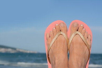 Photo of Woman wearing flip flops near sea, closeup. Space for text