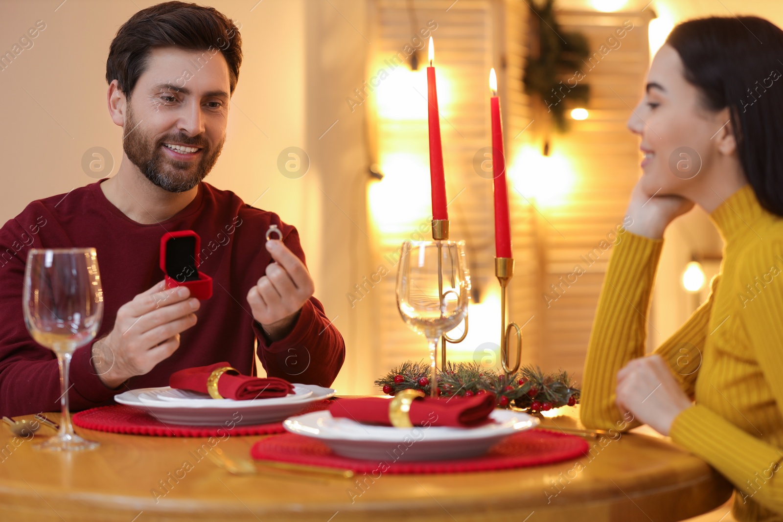 Photo of Man with engagement ring making proposal to his girlfriend at home on Christmas, selective focus