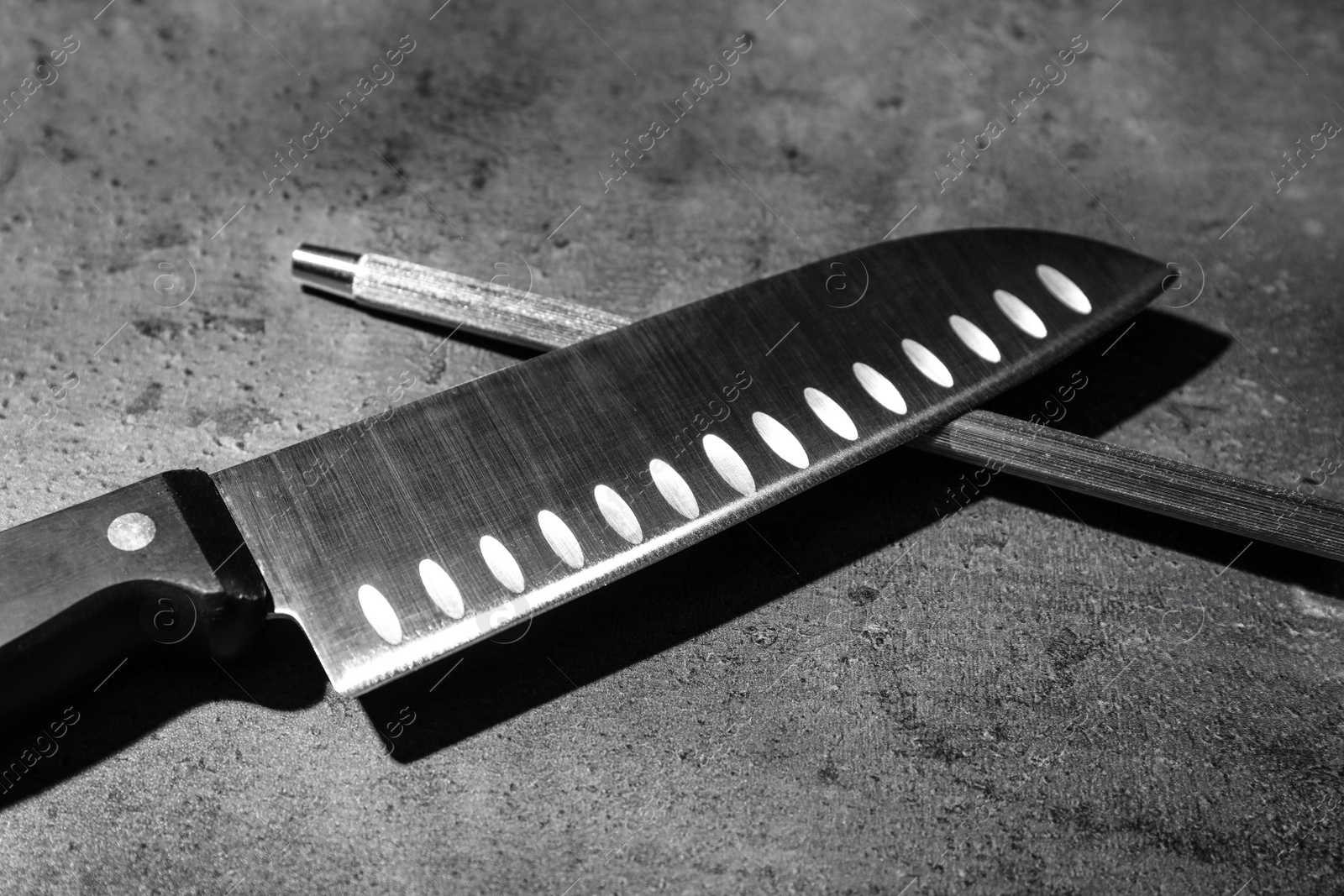 Photo of Santoku knife and sharpener on grey background