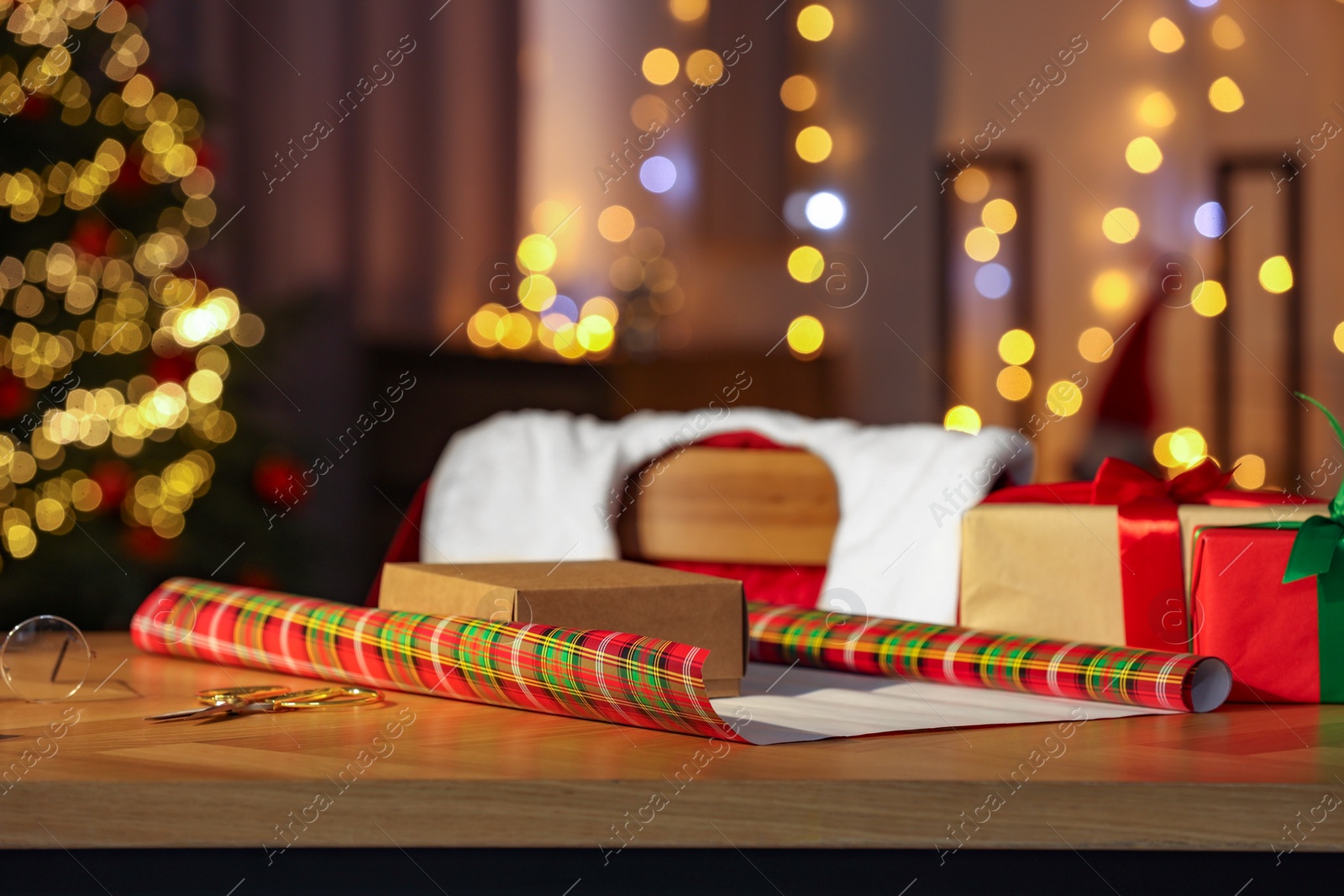 Photo of Santa's Claus workplace. Gift boxes and wrapping paper on table in room with Christmas decor